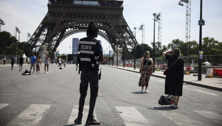 A security officer watches people taking photographs in front of the Eiffel Tower ahead of the 2024 Summer Olympics, Saturday, July 20, 2024, in Paris, France. Three days before the start of the Olympics, France&apos;s Interior Minister has hailed the country’s law enforcement for their hard work in making the Paris Games safe for 10,500 athletes and millions of visitors. (AP Photo/Thomas Padilla, File)